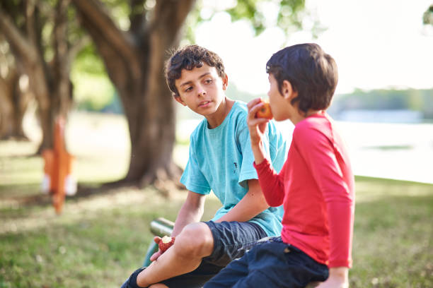 istock Boys in a park, having a healthy snack 2158906307