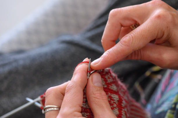 istock woman sitting on sofa, skillfully knitting warm socks 2 2158907524