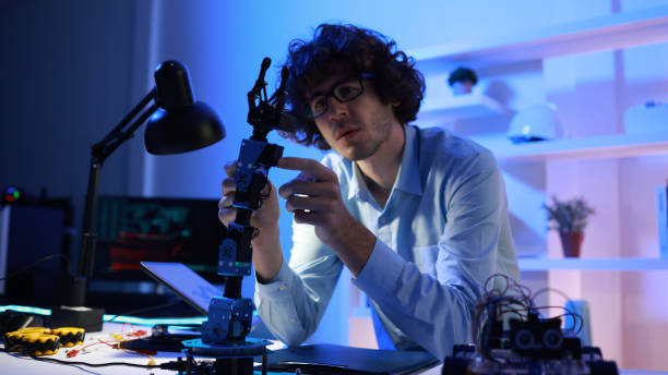 istock Male mechanical engineers analyzing and  controlling robot parameters of a  robot car kit in the  working space home  office 2158909719