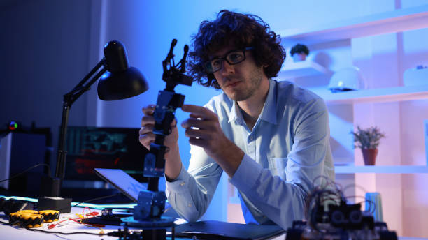 istock Male mechanical engineers analyzing and  controlling robot parameters of a  robot car kit in the  working space home  office 2158909721