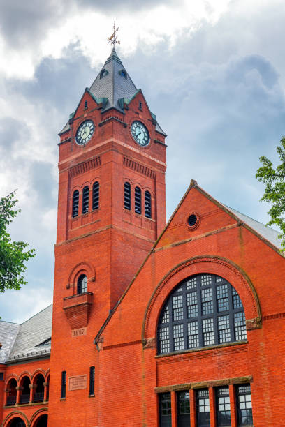 Winchester, Massachusetts, USA - June 12, 2024: The Winchester Town Hall is a historic town hall on Mount Vernon Street in Winchester, Massachusetts. The two and one half  story brick building was built in 1887. Stylistically the building has Queen Anne and Romanesque Revival styling. Its most prominent feature is the clock tower, a four-plus story square tower topped by a pointed roof with gables. Winchester is a town located 8.2 miles north of downtown Boston. Located in Middlesex County, it is one of the wealthiest towns in Massachusetts.
