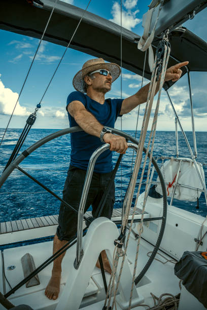 istock A man wearing a straw hat is driving a sailboat and enjoying it. 2158913413