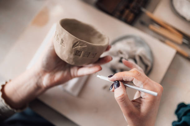 istock Close up of pottery artisan's hands decorating earthenware at studio. 2158915278