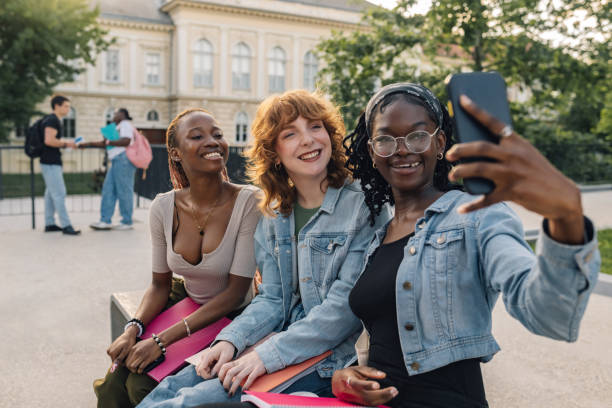 istock Portrait of diverse students talking selfie while sitting at campus. 2158915320