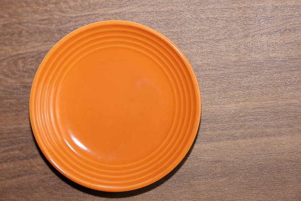Empty orange plate on wooden background.