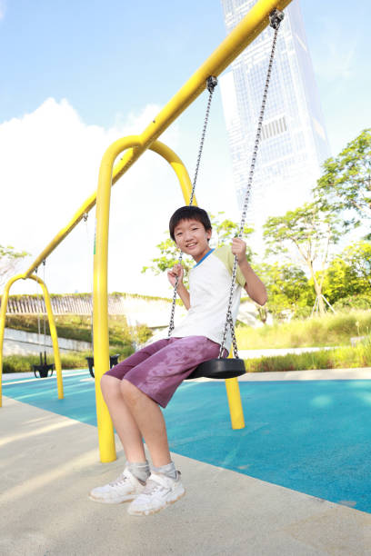 Boy has fun swinging in the city playground