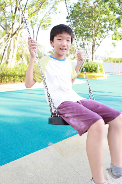 Boy has fun swinging in the city playground