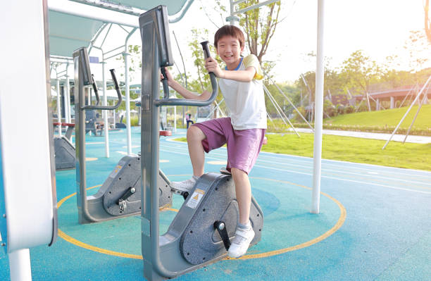Boy riding an exercise bike in the park on a sunny day