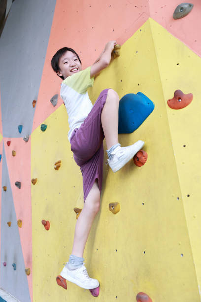 Happy child climbing on artificial rock wall on playground without the use of ropes or harnesses