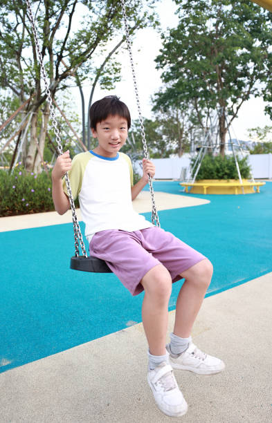 Boy has fun swinging in the city playground