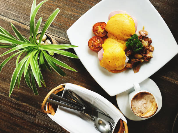 Eggs benedict with bacon and mushrooms on wooden table