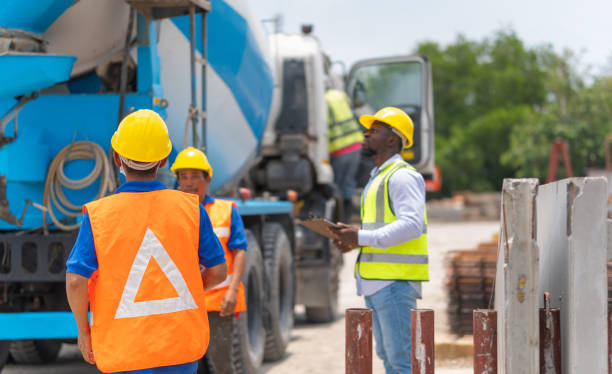 istock Foreman and workers team meeting for planning project at construction site, Site manager and builder control concrete truck mixer on construction site 2158929911