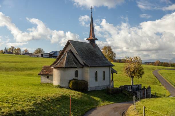 istock picturesque countryside chapel with a steeple surrounded by green fields under a partly cloudy sky 2158932548