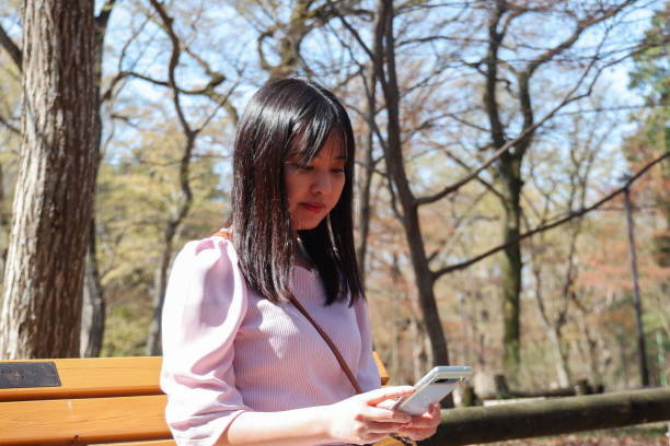 istock Beautiful woman checking mobile phone at spring park 2158932595