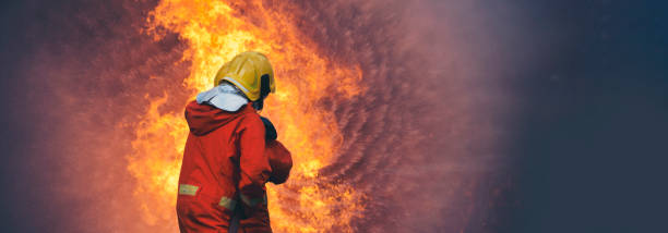istock Firefighter fighting smoke flame use fire hose chemical water foam spray engine. Firefighter Rescue training in fire fighting extinguisher. Fireman wear hard hat safety suit uniform for protection 2158932746