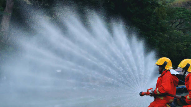 Firefighter Rescue team training in fire fighting extinguisher. Teamwork Firefighter fighting with flame using fire hose chemical water foam spray engine. Fireman teams wear hard hat safety uniform