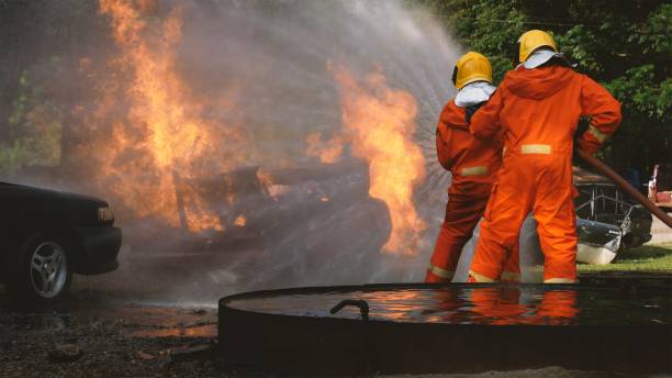 Firefighters using fire hose extinguishing burning fire in factory