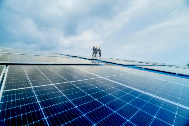 engineer man inspects construction of solar cell panel or photovoltaic cell by electronic device. industrial renewable energy of green power. factory worker working on tower roof. - sonnenkollektor stock-fotos und bilder