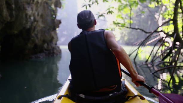 istock Man passes narrow area surrounded by cliff and dense trees 2158940815