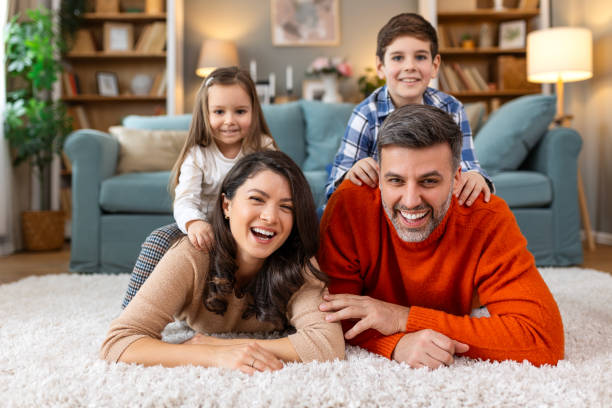 istock Happy parents and their small kids talking while lying on carpet at home. 2158942508