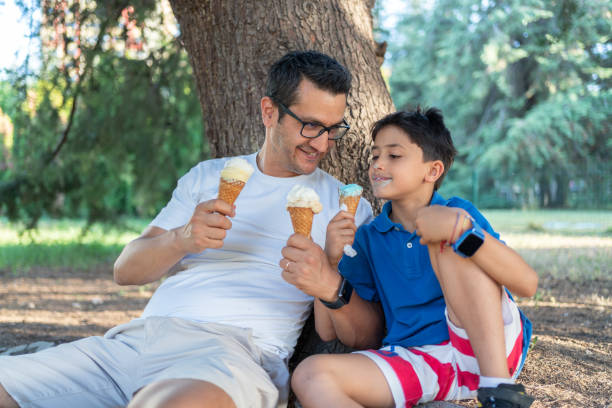 istock Father And Son Enjoying Ice Cream In Public Park 2158942994