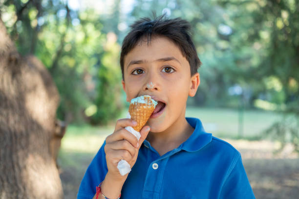 Boy eating an ice cream with chocolate flake and caramel topping.