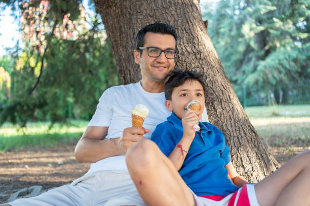 istock Father And Son Enjoying Ice Cream In Public Park 2158943098