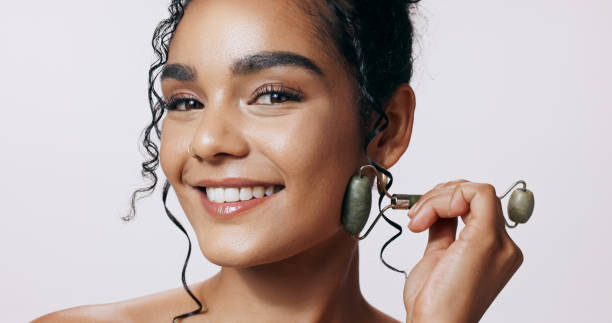 istock Face roller, smile and woman with cosmetics, glow and makeup on grey studio background. Portrait, happy person and model with tool, wellness and beauty with skincare, dermatology and grooming routine 2158944162