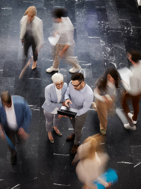 istock Above view of entrepreneurs using laptop among colleagues in blurred motion. 2158944861