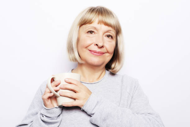 istock old excited lady smiling laughing, holding cup drinking coffee, tea, beverage on white background 2158945532