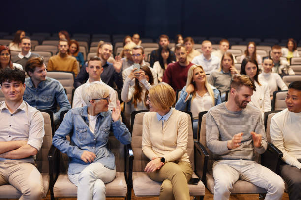 Multiracial group of excited young people in the cinema or theater, watching, laughing.