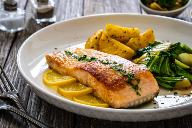 istock Fried salmon, fried potatatoes with stir-fried bok choy on wooden table 2158946406