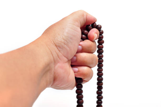 Close-up of hands holding prayer beads white background