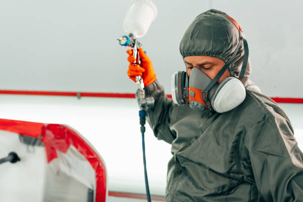 istock Auto mechanic worker wearing protective workwear spraying white paint on car part at workshop 2158946603