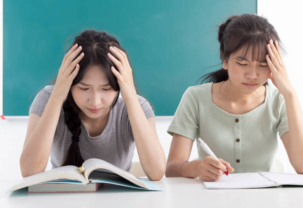 tired upset student girls grabbing head  in classroom