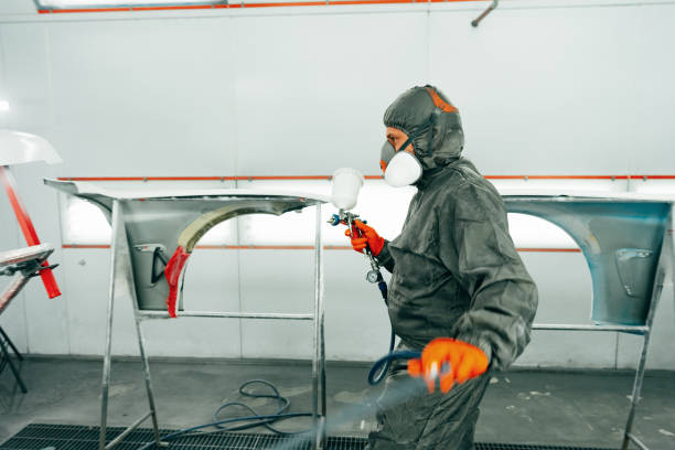 istock Auto painter painting a car with vaporizer gun inside a paint booth 2158947342
