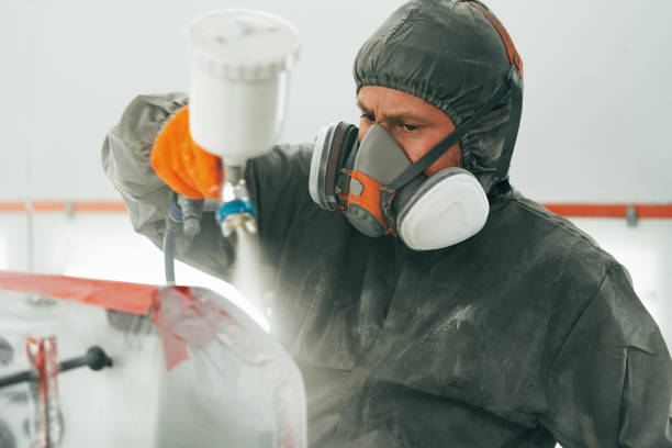 istock Auto painter painting a car with vaporizer gun inside a paint booth 2158947571