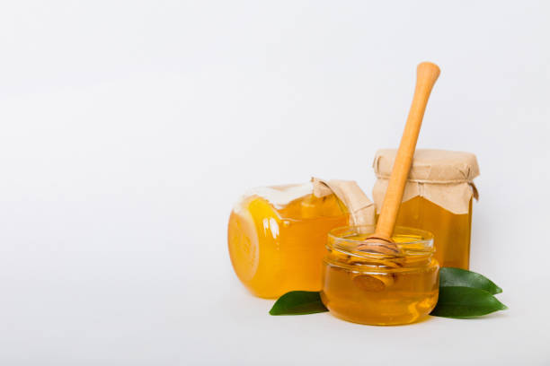 istock Honey in jar with leaves and honey dipper on colored background top view with copy text 2158948410