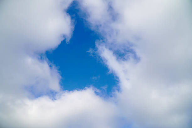 A hole in the white clouds, which is visible the blue sky. Soft focus