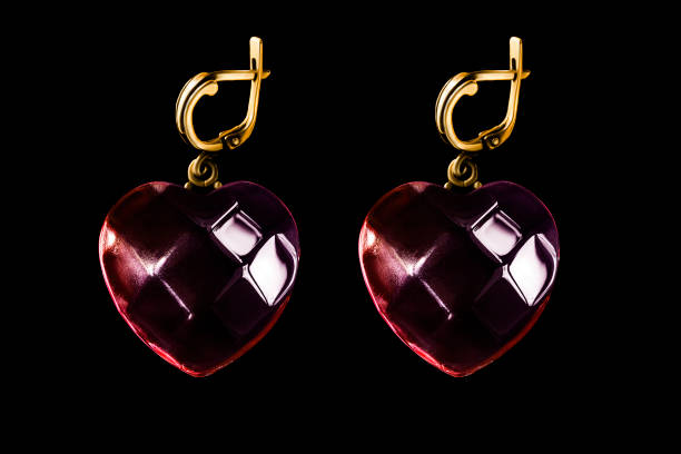 Red crystal heart shaped golden earrings isolated on black background
