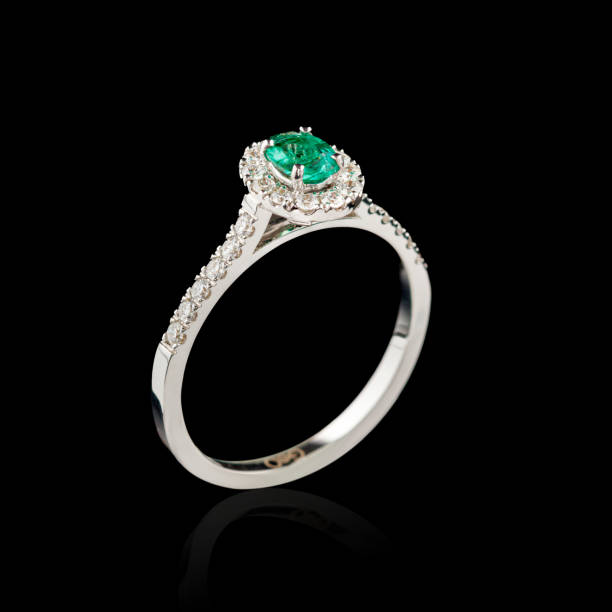istock Beautiful white gold ring with diamonds and emerald on a black background 2158950912