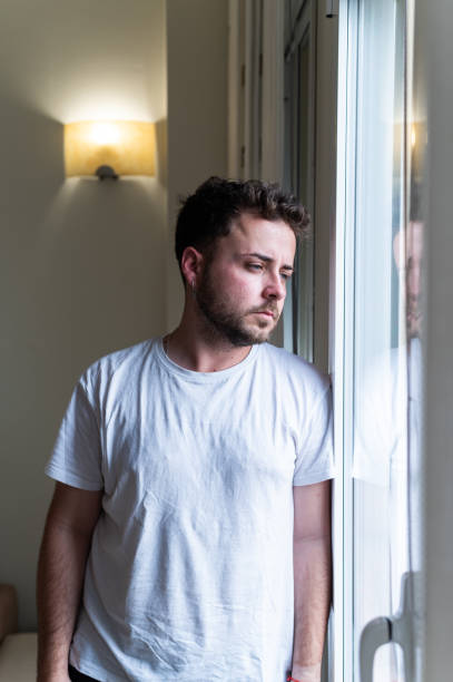 istock Man standing looking thought the window from home 2158951179