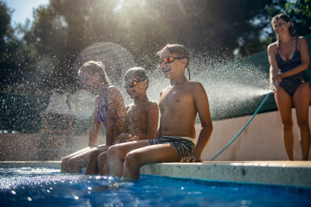 istock Mother splashing kids with garden hose 2158952594