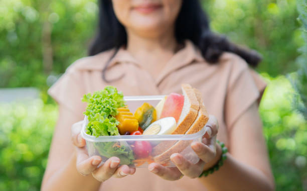 istock Close up Woman holding lunch box over nature background. 2158955332