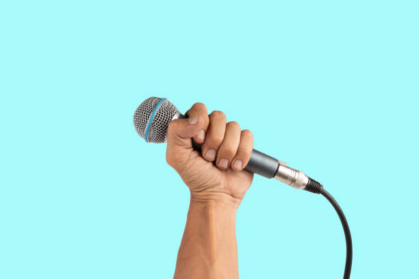 istock Black male hand holding a microphone isolated on light cyan background 2158956109