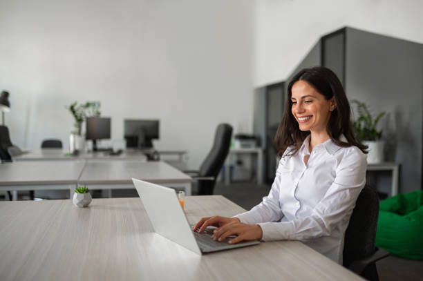 istock Young female entrepreneur smiling and working on her lap top in modern workspace 2158956729