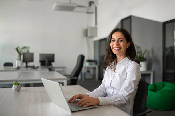 istock Young female entrepreneur smiling and working on her lap top in modern workspace 2158956758
