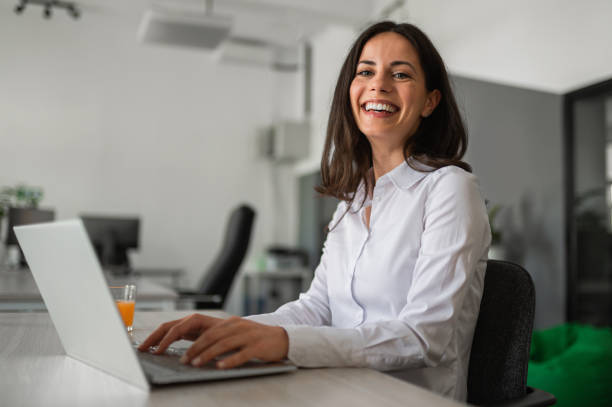 istock Young female entrepreneur smiling and working on her lap top in modern workspace 2158956765