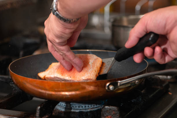 istock Cook preparing salmon in frying pan 2158959957