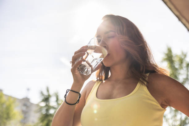 Thirsty sportswoman drinks water after running for hydration during tropical heat.